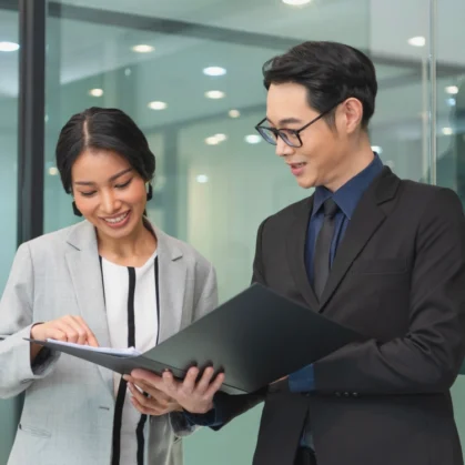 Smiling asian business woman showing document report to her manager during office meeting.